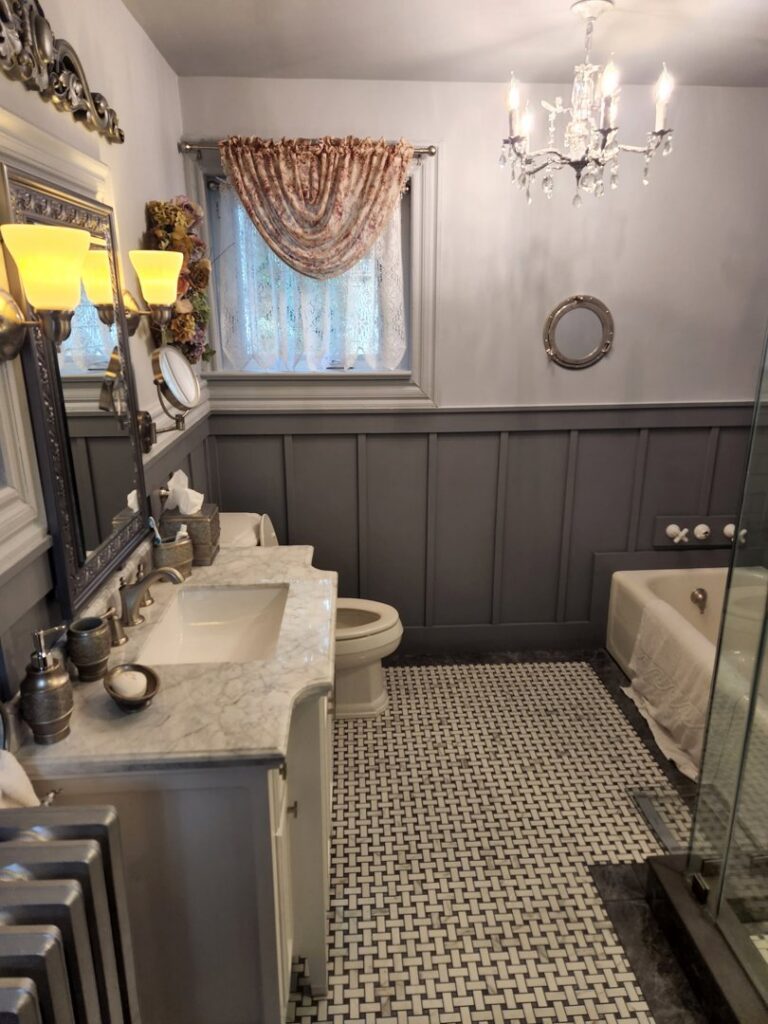 A beautifully remodeled traditional bathroom featuring wainscoting, a new vanity, and basketweave floor tiles by Ace Tile & Finishing LLC in Philadelphia, PA.