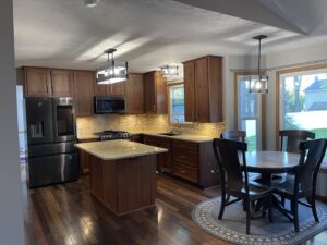 A traditional kitchen remodel featuring dark wood cabinets, a kitchen island, and a dining area by CLE Remodeling Co in Cleveland, OH.