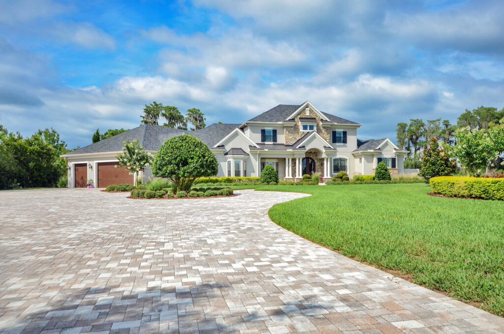 A grand traditional luxury home exterior with a large paved driveway and manicured lawn by TamLin Homes Inc in Tampa, FL