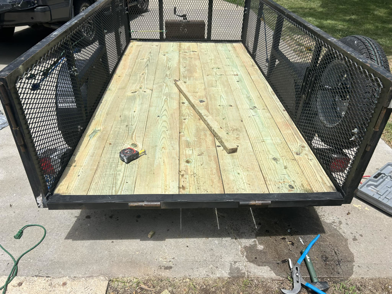 Handyman repairing a trailer deck with new wood planks for Norbe's Home Solutions LLC in Lenexa, KS.