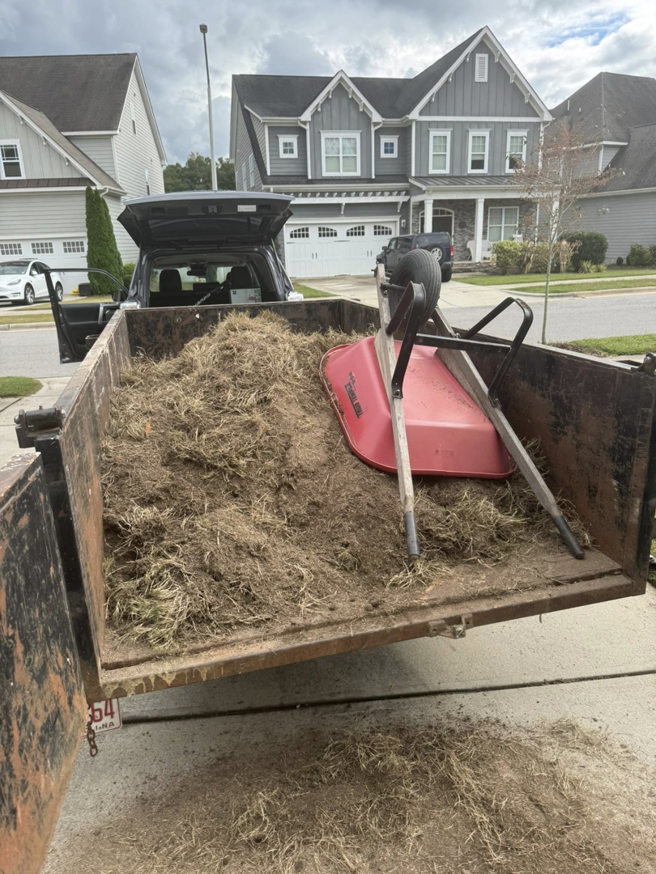 A trailer loaded with dried grass and sod, along with a wheelbarrow, for removal by JR's Rapid Junk Removal in Cary, NC