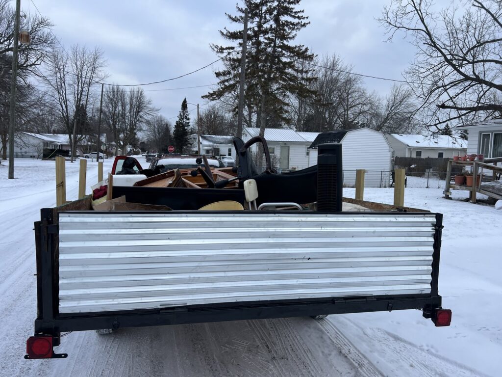 A trailer loaded with various items like furniture and wood, showcasing a junk removal job by Feelin Good Junk Removal & Estate Sales at 1111 Debra Lane.