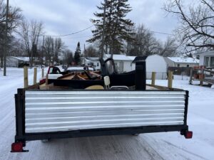 A trailer loaded with various items like furniture and wood, showcasing a junk removal job by Feelin Good Junk Removal & Estate Sales at 1111 Debra Lane.