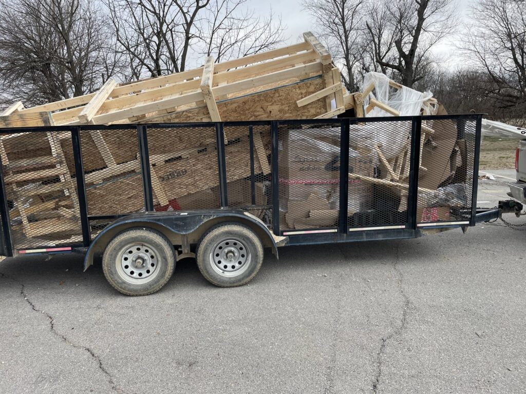 A utility trailer overflowing with construction debris, including wood and cardboard, for removal by DC'S Removal Service in Neelyville, MO.