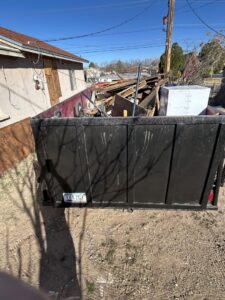 A large open-top trailer filled with construction debris and various junk, being hauled by Discount Hauling in Las Cruces, NM.