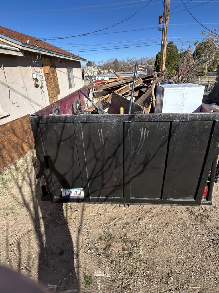 A large open-top trailer filled with construction debris and various junk, being hauled by Discount Hauling in Las Cruces, NM.