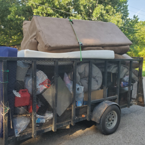 A trailer filled with old furniture and various junk items, ready for hauling by Urban Junk Removal, LLC in Springdale, AR.