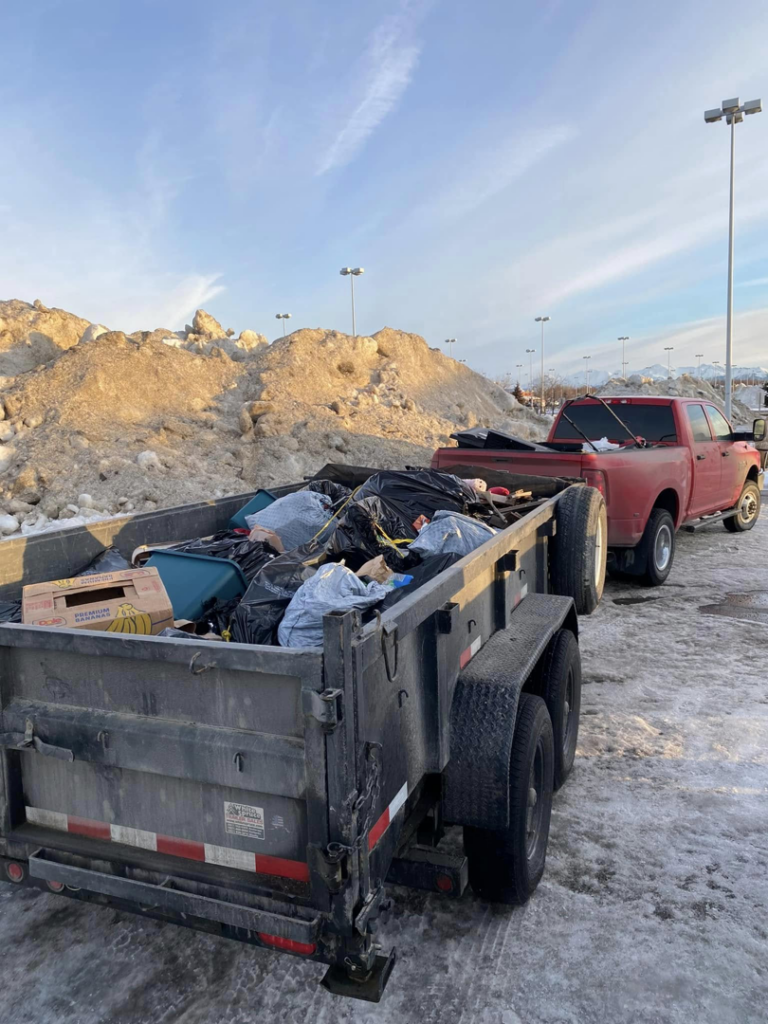 A trailer full of black trash bags and various junk items being hauled by Haul-Away in Anchorage, AK.