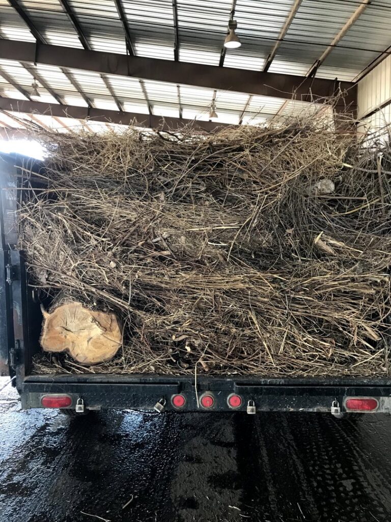 A Haul It All Services trailer full of junk parked in front of a residential garage in Albuquerque, NM