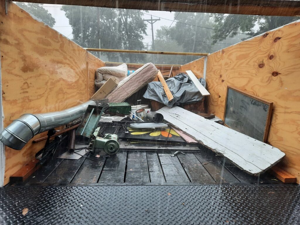 A trailer loaded with various junk items including a mattress, wood, and metal, being removed by Sunshine junk removal LLC in Lake City, MN.