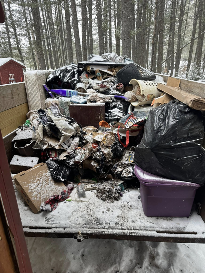 A trailer filled with various junk items on a snowy day by CleanSite Solutions in Windham, ME.