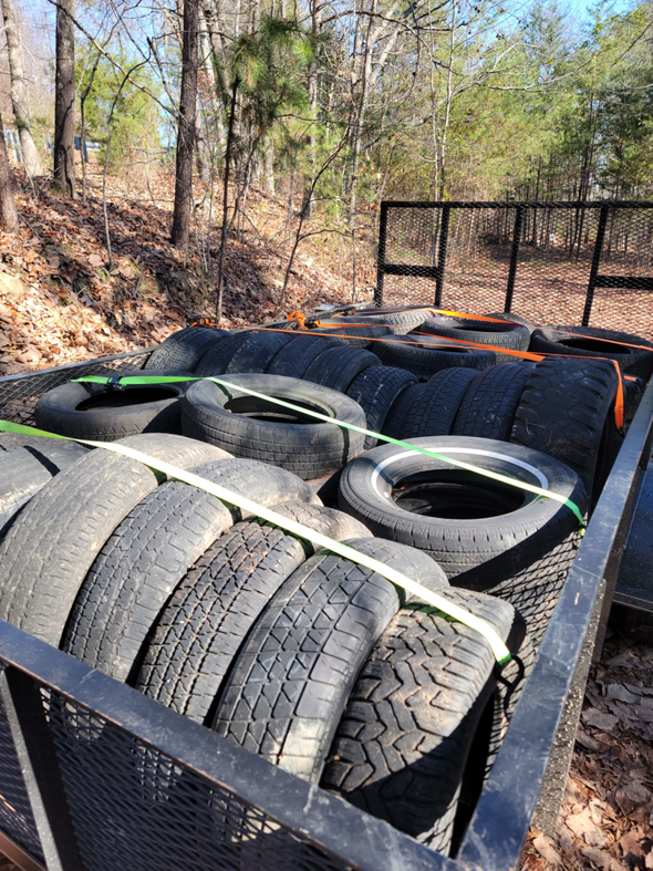 A trailer loaded with numerous old tires, secured with straps for junk removal by Haulin' Junk Chattanooga in Chattanooga, TN.
