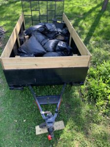 A trailer filled with black trash bags and various junk items, ready for removal by Mr. Groundhog Disposal and Services in Bloomington, MN.