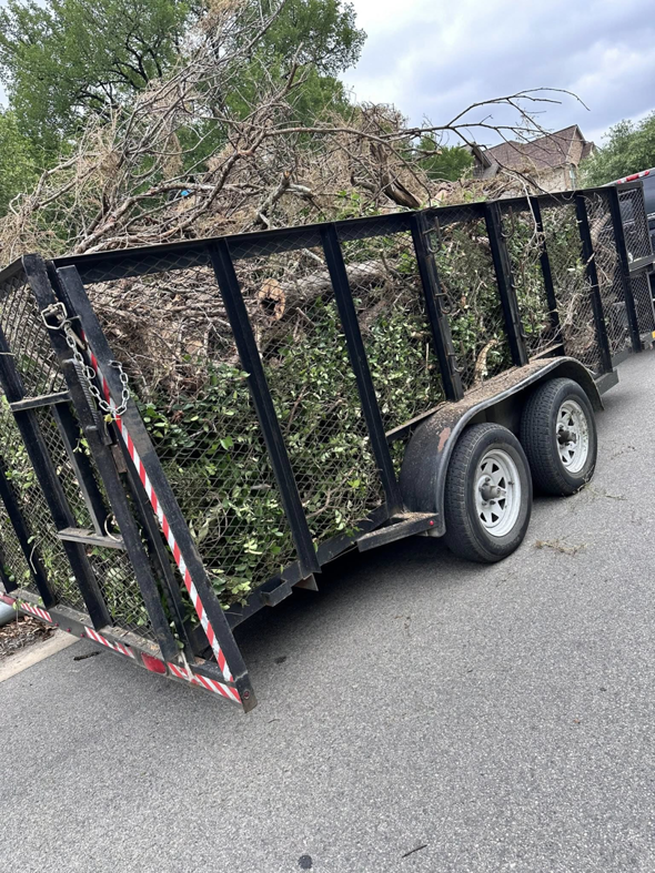 A utility trailer filled with tree branches and debris after a tree service job by Alvarado Lawn Care & Tree Service in San Antonio, TX