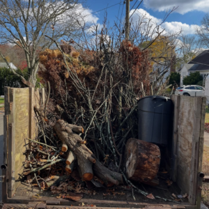 A trailer filled with yard waste, including branches, logs, and a trash can, ready for removal by DLS Junk Removal in Waterbury, CT.