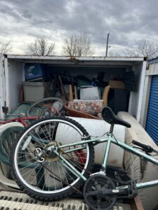 A trailer loaded with a bicycle, mattress, and various household junk items, showcasing a removal service by Empty It Out Junk Removal, LLC in Billings, MT.