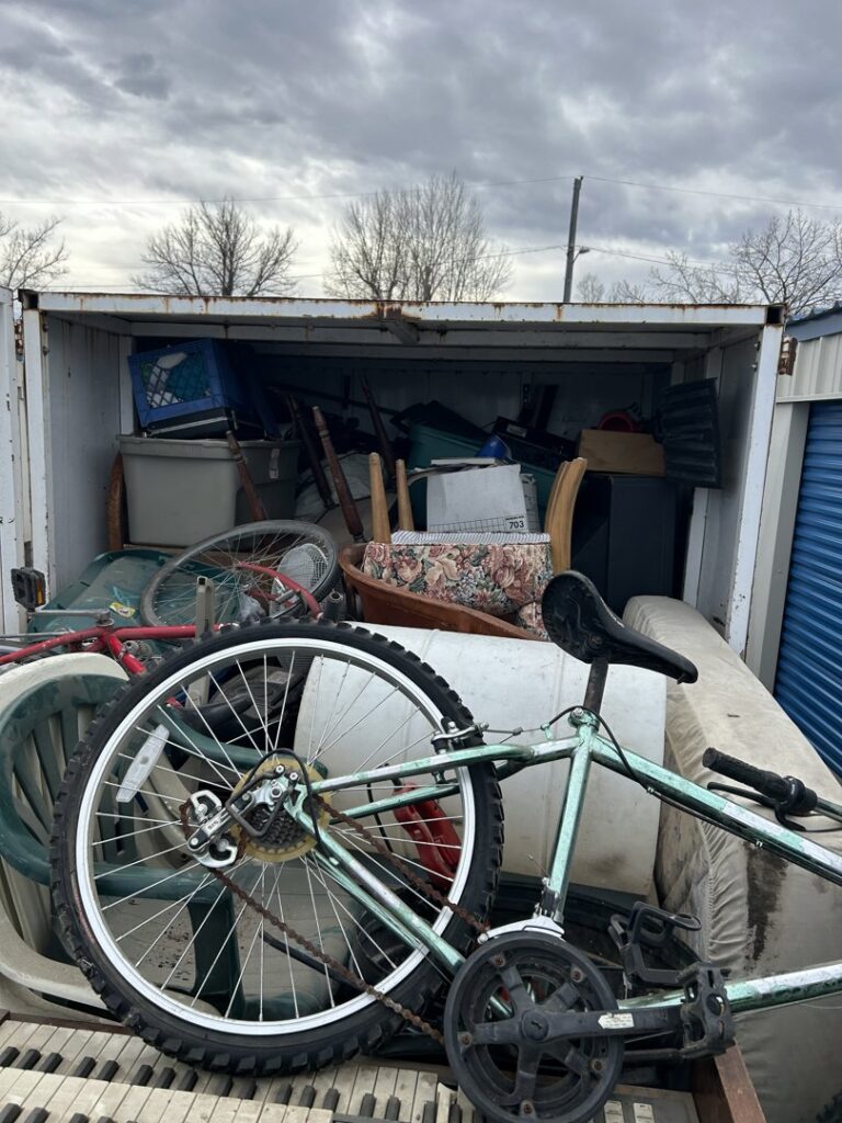 A trailer loaded with a bicycle, mattress, and various household junk items, showcasing a removal service by Empty It Out Junk Removal, LLC in Billings, MT.