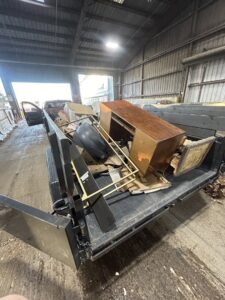 A junk removal trailer loaded with old furniture and debris inside a warehouse facility by Reno Junk Pros in Reno, NV.