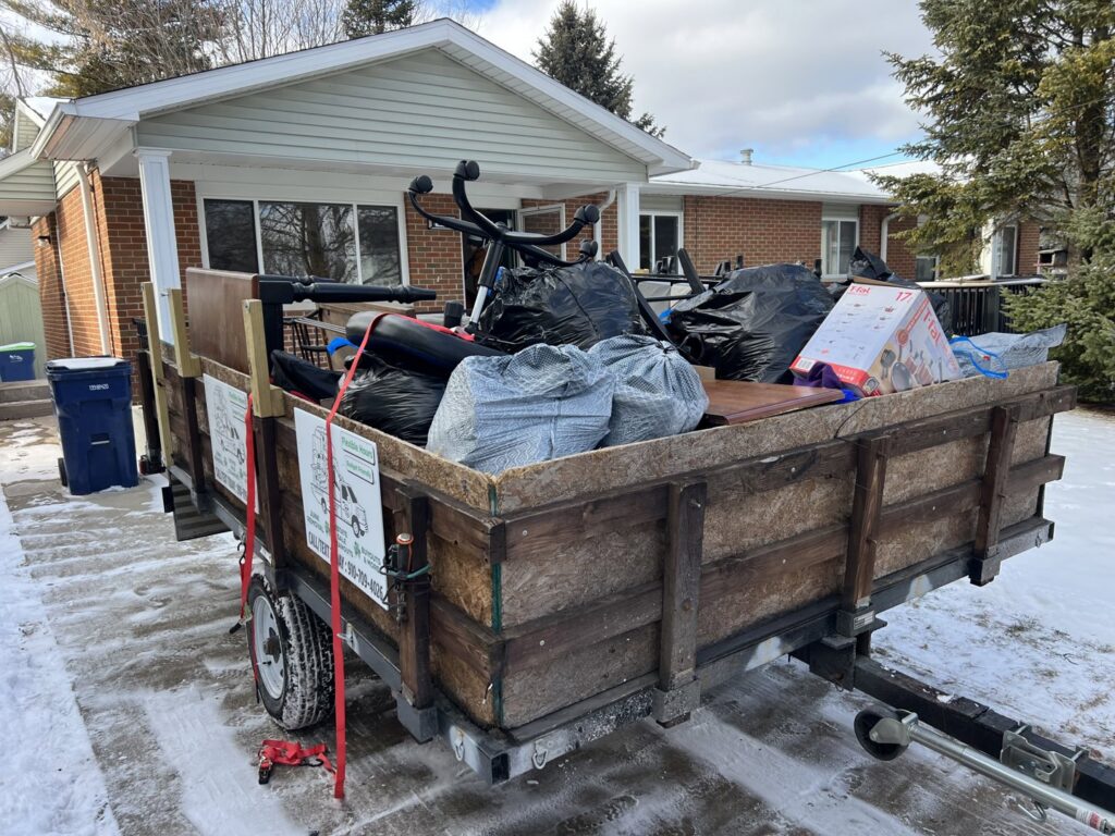 A trailer loaded with black trash bags and other items, showcasing a junk removal job by Feelin Good Junk Removal & Estate Sales at 1111 Debra Lane.