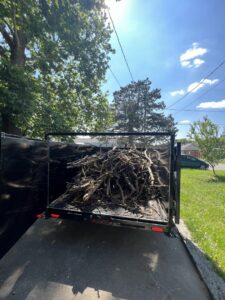 A trailer loaded with tree branches and yard waste, handled by Vargas Junk Removal & Dumpster Rentals in Urbandale, IA.