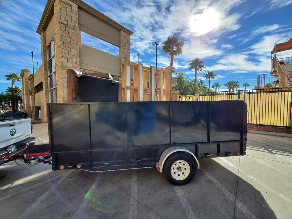 A utility trailer loaded with bulky furniture and wooden items for removal by V.S.C Junk Removal Services in Las Vegas, NV.