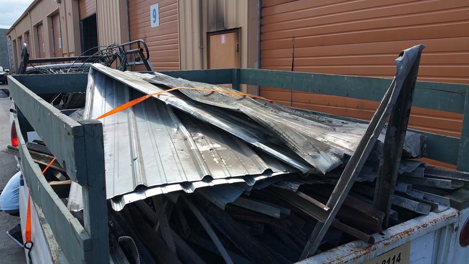 A trailer loaded with corrugated metal sheets and other construction debris, ready for removal by Down and Dirty Junk Removal in Tacoma, WA.