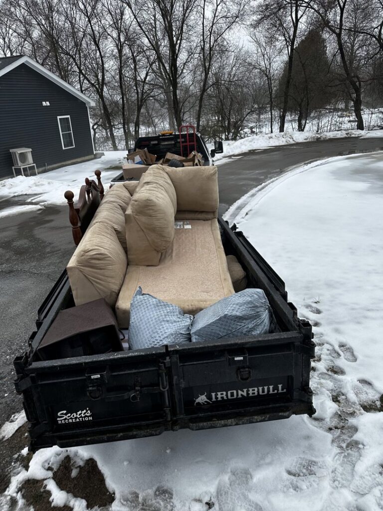 A trailer loaded with furniture including a couch, mattress, and bed frame for junk removal by O'Brien Property Services in Clay, NY.