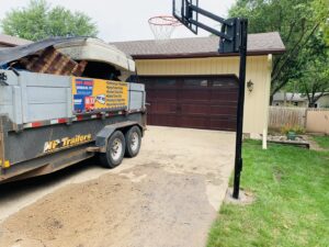 A trailer branded with "WeHaul It!" loaded with a mattress and other junk, ready for transport by WeHaul Hauling & Junk Removal in Sioux Falls, SD.
