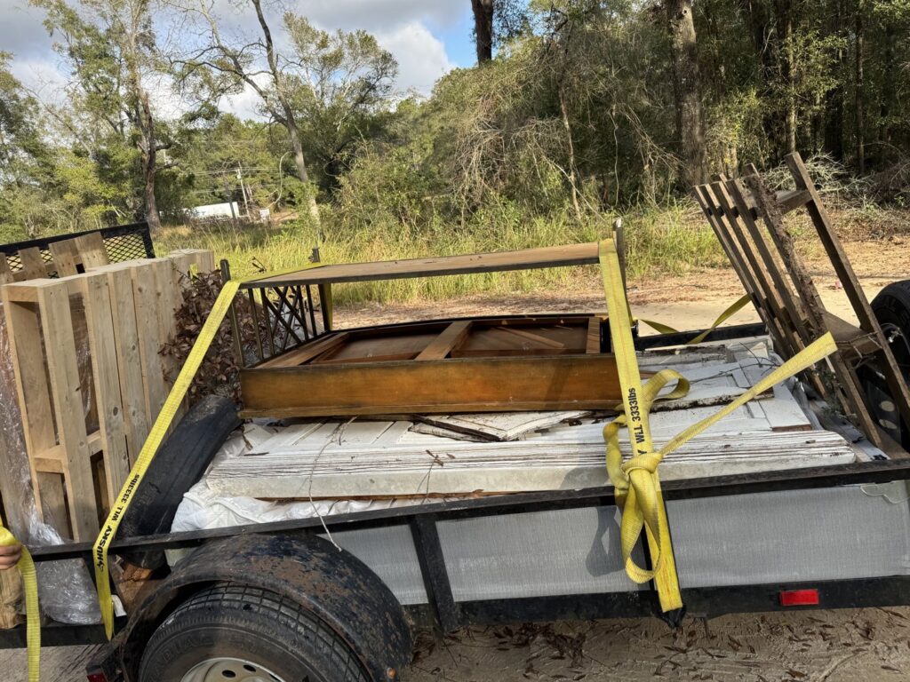 A trailer loaded with pallets, wood, and various debris, secured for transport by L.P.Z Trash & Junk Removal in Tallahassee, FL.