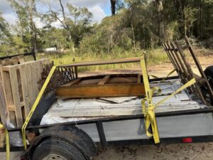 A trailer loaded with pallets, wood, and various debris, secured for transport by L.P.Z Trash & Junk Removal in Tallahassee, FL.