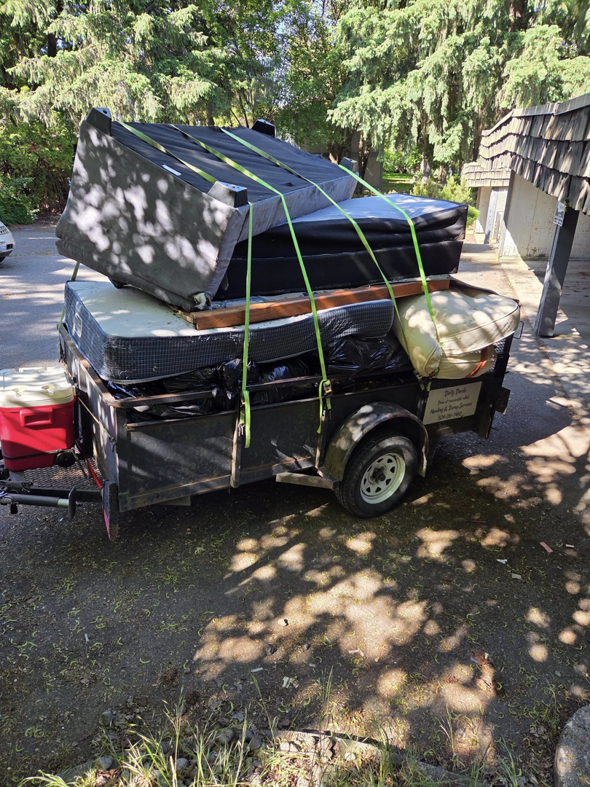 A trailer loaded with mattresses, furniture, and various junk items for removal by Dirty Deeds Trash Removal Service in Annandale, VA.
