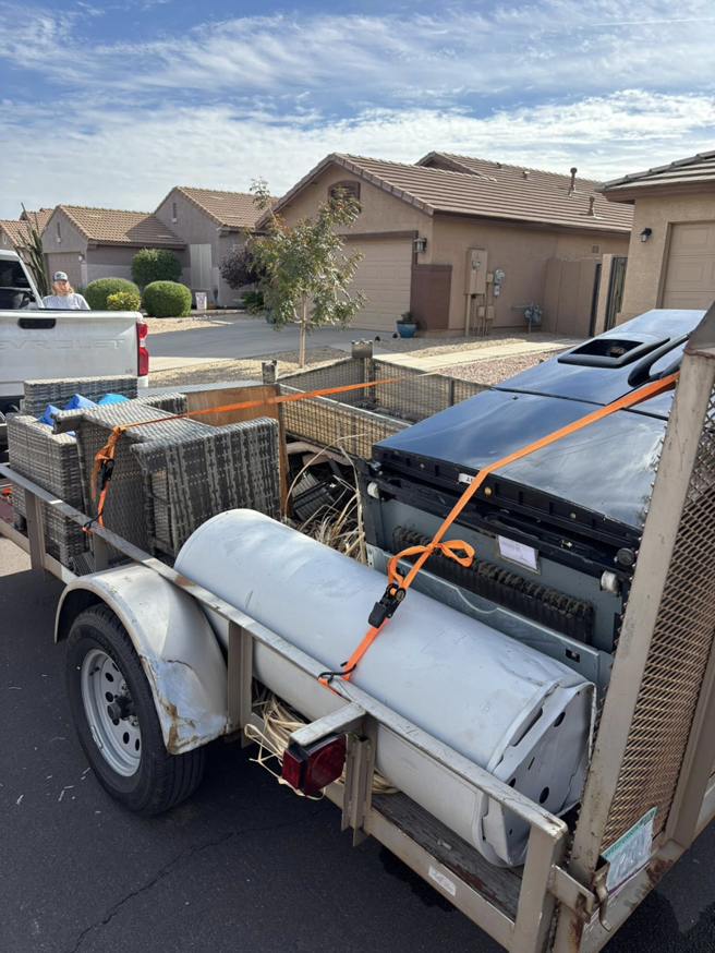 A trailer loaded with a water heater, furniture, and other junk items ready for removal by Bin There Junk That in Phoenix, AZ.
