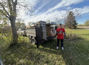A Junk Haulin Heroes team member standing next to a trailer loaded with mattresses and other junk for removal in Bismarck, ND.