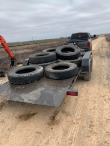 A trailer loaded with numerous old tires being hauled away for disposal by Junk something ATX in Austin, TX
