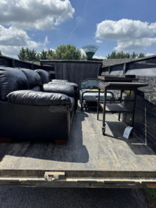 A trailer loaded with a black sofa, grill, and other items for removal by Quick Lift Junk Removal in Hagerstown, MD.