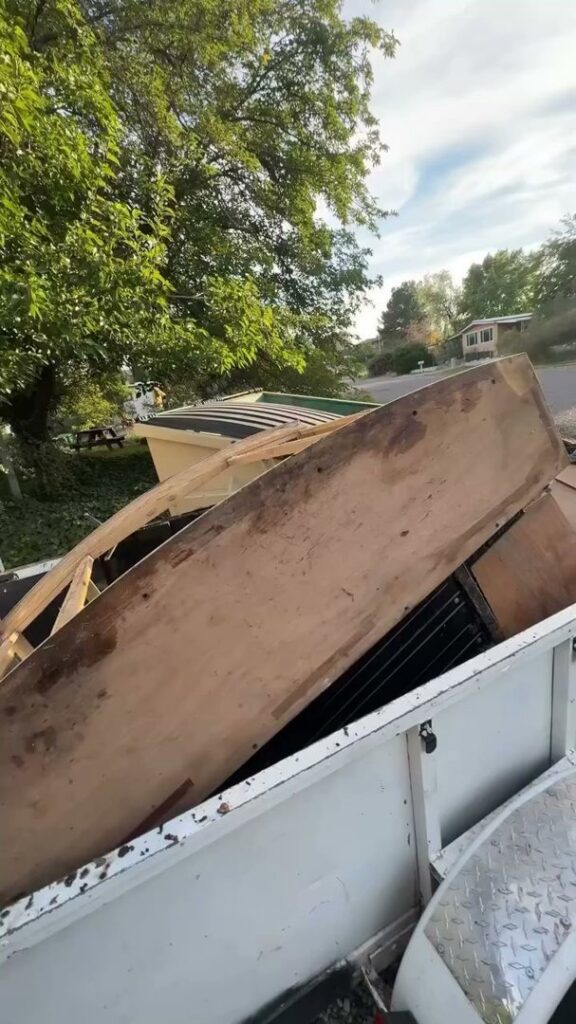 A utility trailer loaded with wooden planks and various debris, demonstrating junk removal by richartehelps in Scottsdale, AZ.