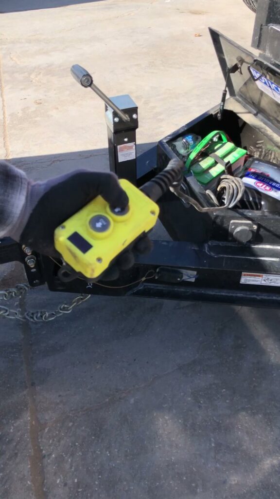 A gloved hand operating a remote control for a trailer, demonstrating equipment used by MLG Strong Hauling & Junk Removal LLC in Henderson, NV.