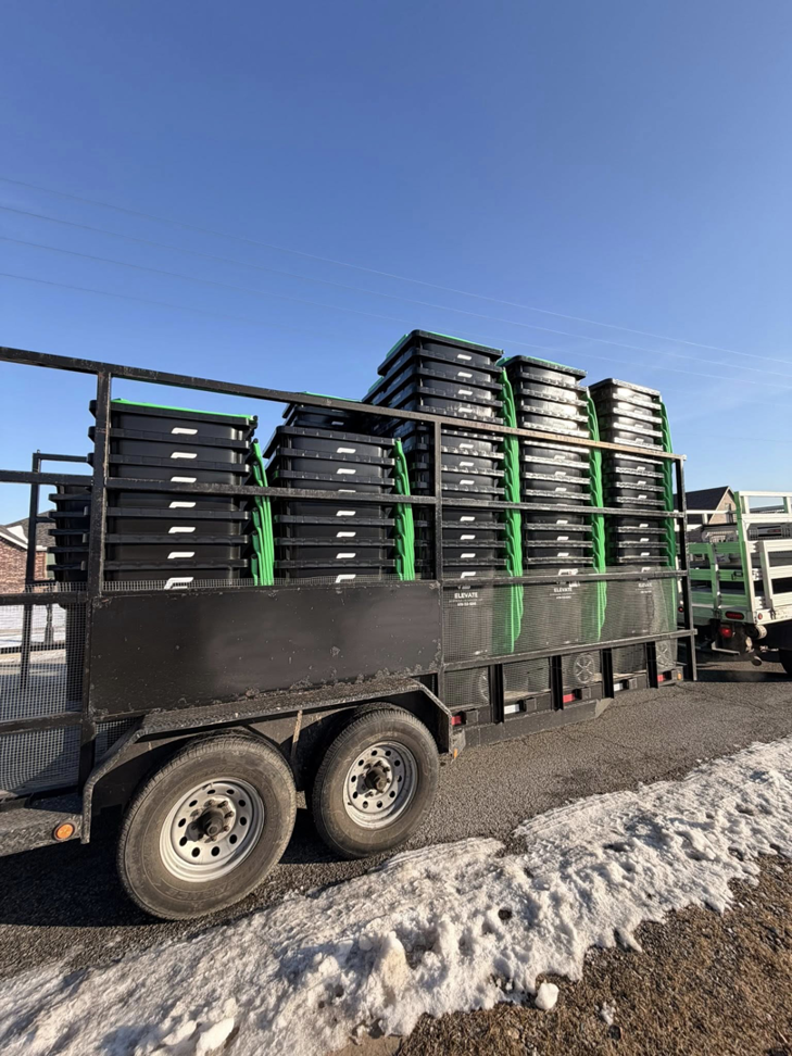 A trailer stacked high with black disposal bins for Elevate Disposal Services, LLC in Bentonville, AR