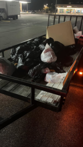 A utility trailer loaded with many black trash bags and a piece of furniture, collected by Resilient Trash and Cleaning LLC in New Orleans, LA.