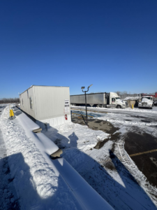 A snowy view of the Riverbend Recycling and Transfer Station yard with semi-trucks and a scale house in Independence, MO.