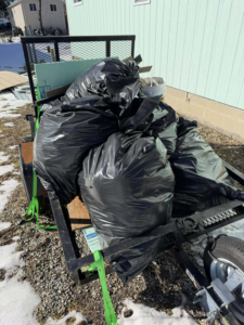 A utility trailer filled with numerous black trash bags for junk removal by Curtis Rose Companies LLC in Janesville, WI.