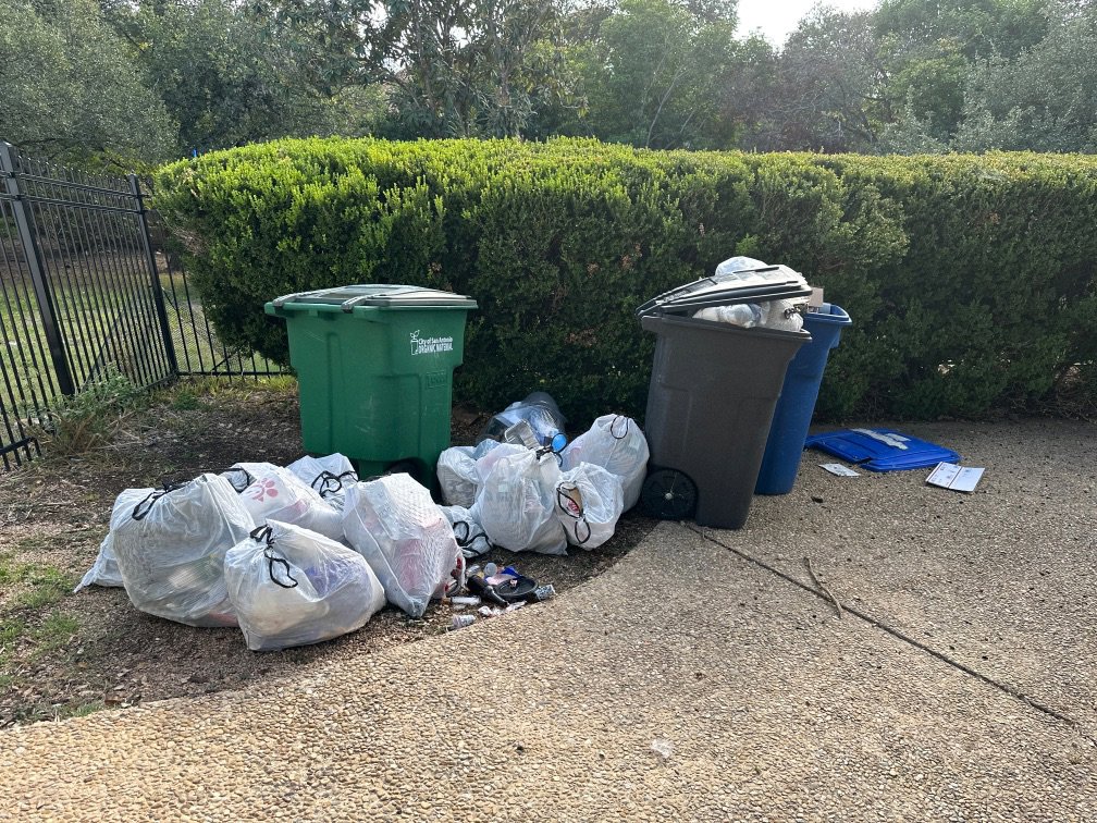 Multiple trash bags and loose items placed curbside for pickup by SATX Junk-A-Haulics in San Antonio, TX.