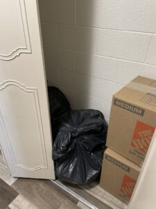 Black trash bags and moving boxes stacked in a corner, ready for removal by Missoula Junk Removal, LLC in Missoula, MT.