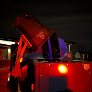 A Southeast Aquatics Trash bin being emptied into a garbage truck at night in Raleigh, NC.