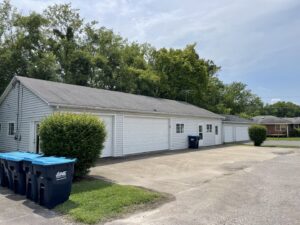Multiple blue trash bins with the One Waste Solutions logo lined up outside a building in Murfreesboro, TN, for waste collection.
