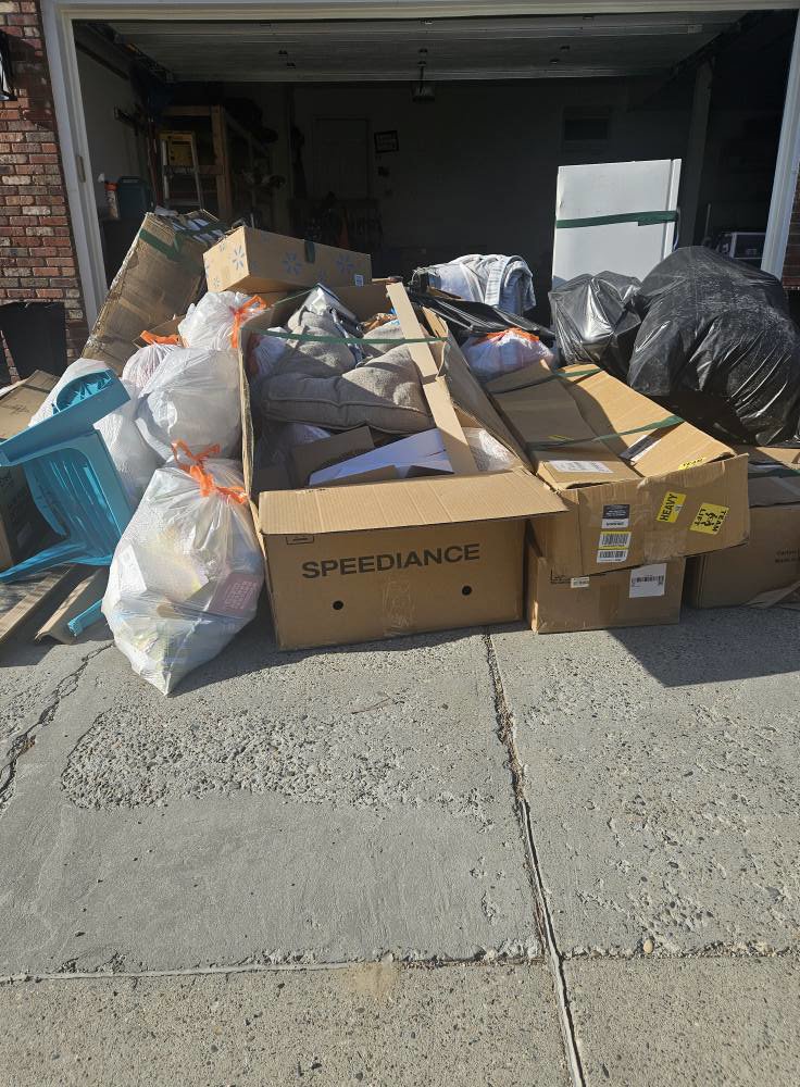 A large pile of bagged trash and cardboard boxes in front of a garage, ready for removal by Big Sky Junk Removal LLC in Billings, MT.