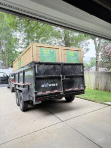 A Trash King LLC dump trailer filled with junk and debris in a residential driveway in Derry, NH.