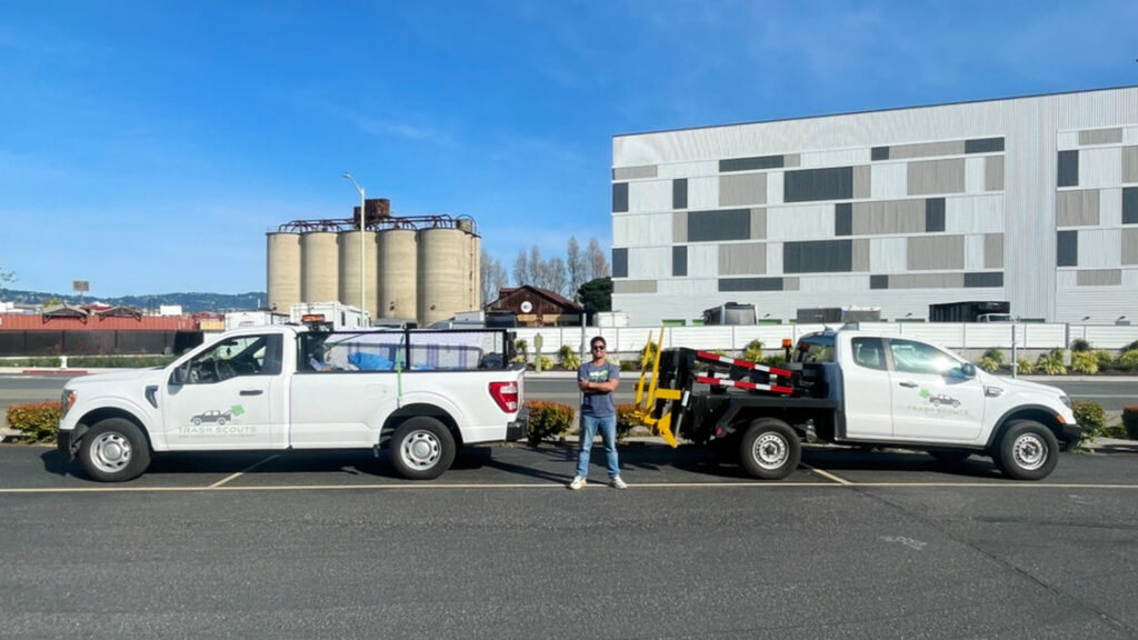 Two white TrashScouts junk removal trucks with specialized equipment parked in Oakland, CA.