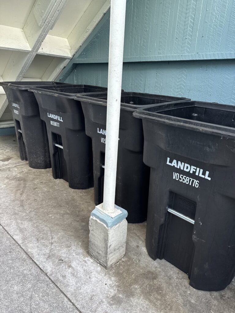 Five black "LANDFILL" waste bins lined up, representing waste management services by TrashScouts in Oakland, CA.