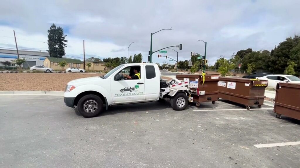 A TrashScouts truck hauling multiple brown dumpsters in Oakland, CA, demonstrating junk removal services.
